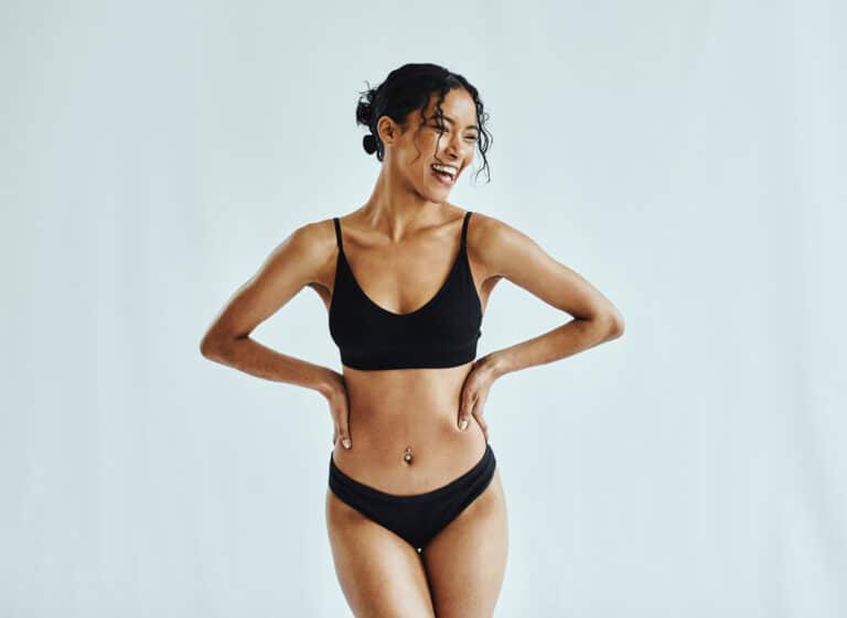 Happy, woman and lingerie in a studio for wellness, beauty and weight loss against a white background mockup. Health, black woman and underwear model posing, laughing and feeling confident mock up